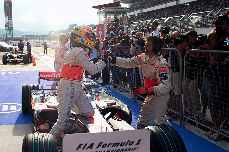 Polesetter Hamilton arrives at parc ferme and is warmly welcomed by a McLaren mechanic