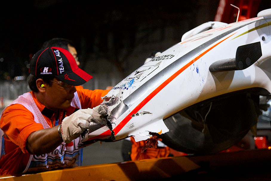 A marshal helps to position Fisichella's damaged Force India car on the tow-away truck