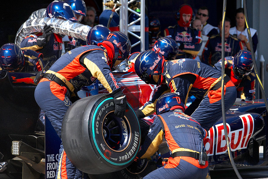 Three Toro Rosso mechanics take care of one of Sebastien Bourdais' tyres during his pit stop