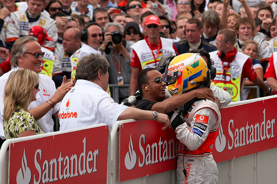 Race winner Hamilton caresses his brother Nicolas at parc ferme fence
