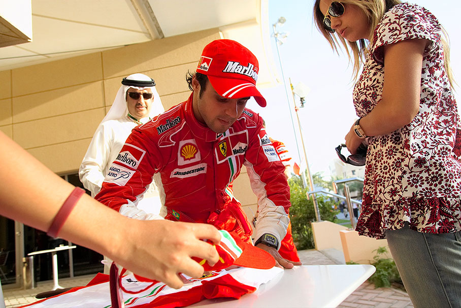 Felipe Massa sign memorabilia for Ferrari VIP guests under the eyes of wife Raffaela