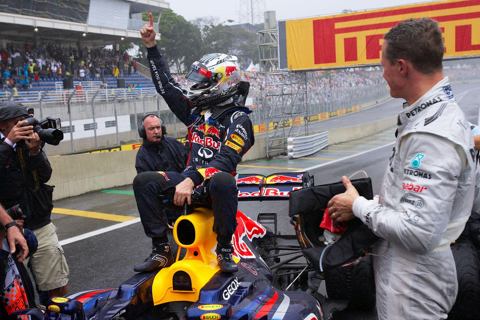 New triple World Champion Sebastian Vettel sits on the Red Bull Racing car and celebrates with leaving Champion Schumacher in parc ferme
