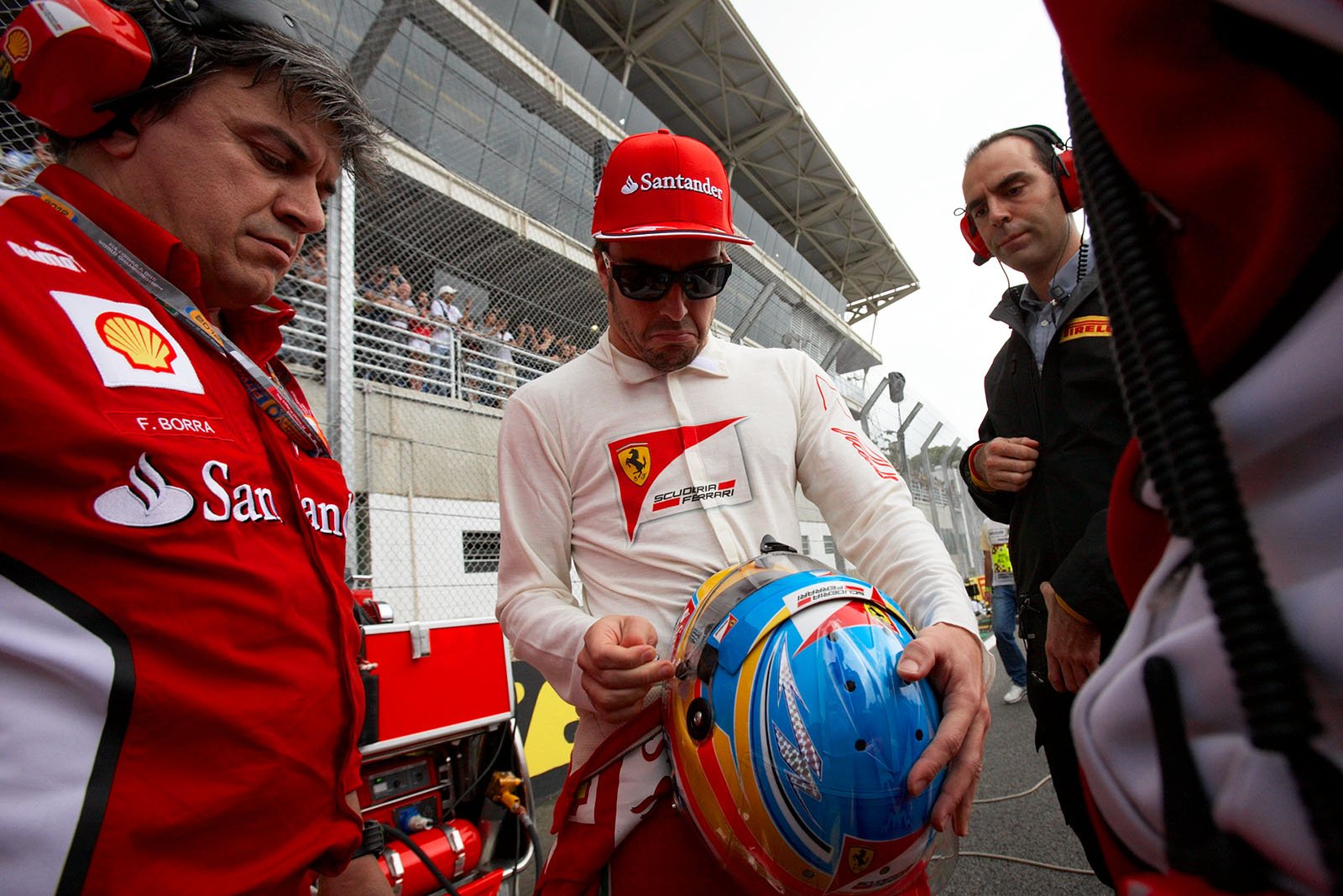 Fernando Alonso, Ferrari, checks his racing helmet besides the grid