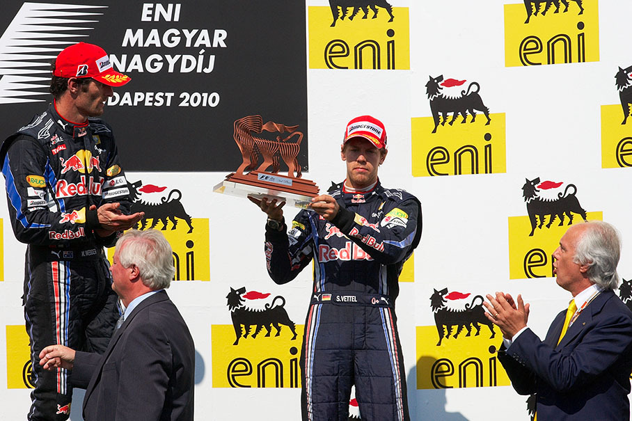 A quite unhappy Sebastian Vettel presents his third place trophy, disappointed after being fined with a drive-through penalty