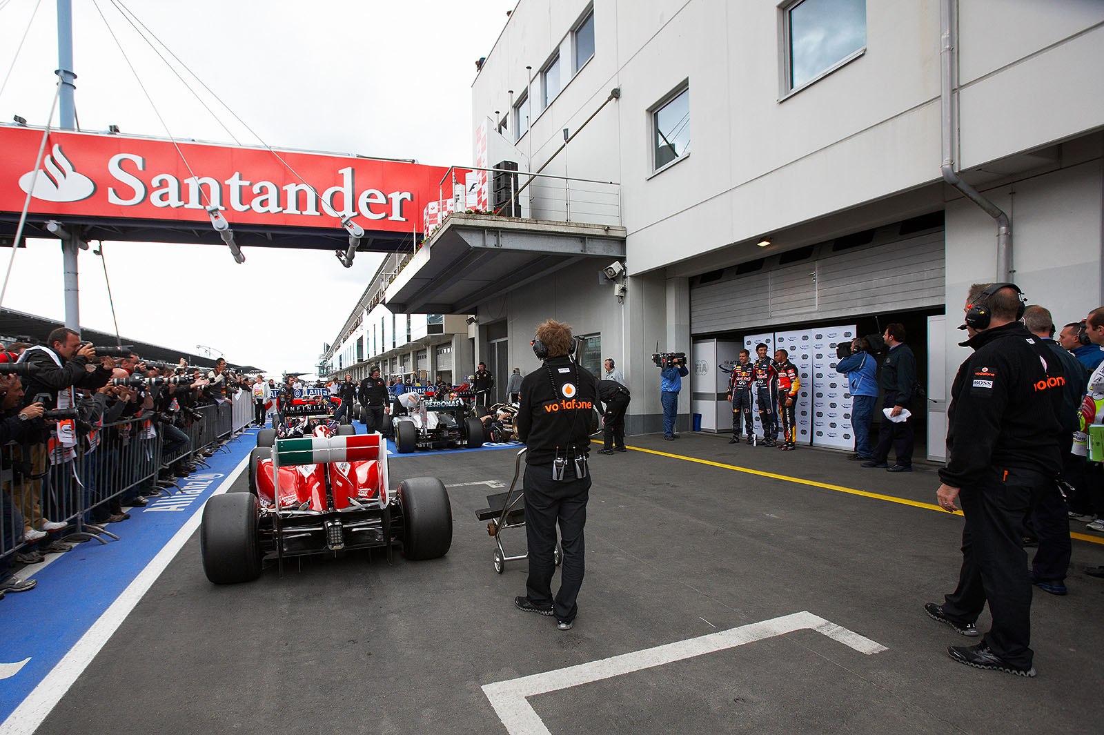 The fastest three qualifiers wave at the world's media behind the cars in parc ferme: on the left hand third qualified Red Bull driver Sebastian Vettel, his team mate Mark Webber as polesetter in the middle and McLaren's Lewis Hamilton as second on the grid