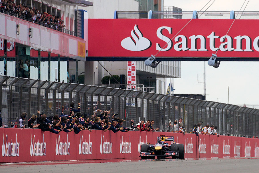 Mark Webber passes his cheering Red Bull team