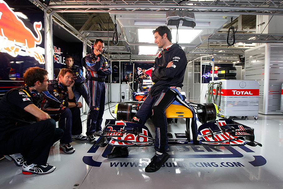 Mark Webber sits on his Red Bull Racing car and chats with the mechanics
