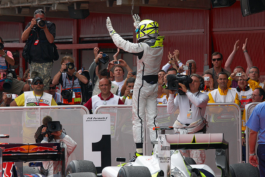 Race winner Jenson Button jumps on his car in parc ferme