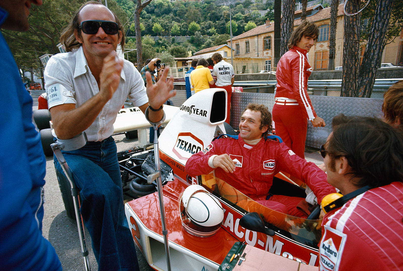 Monaco 1975: McLaren driver Jochen Mass (in his cockpit) jokes around with Mike Hailwood who had left Formula 1 after being injured badly at the 1974 German Grand Prix at the Nurburgring.