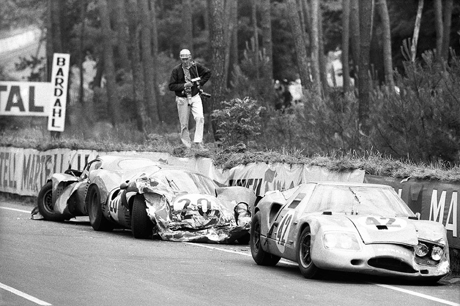 A photographer examines the wrecks of three retired racecars besides the track, car no. 42 is the Matra M620 BRM 03 driven by Jo Schlesser (F) and Alan Rees (GB), car no. 20 the Ferrari 330 P3 #0848 of Mike Parkes (GB) and Ludovico Scarfiotti (I), at the rear car no. 53, the C.D. SP66 Peugeot 663IW75 of Georges Heligouin (F) and Johnny Rives (F).