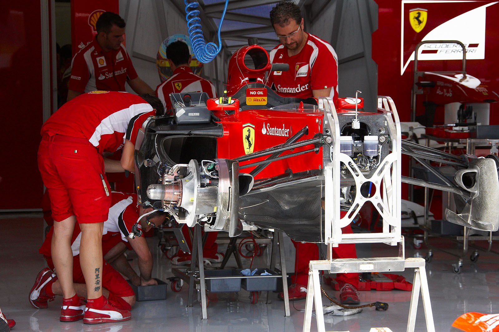 Busy mechanics work in Ferrari pits on Thursday afternoon