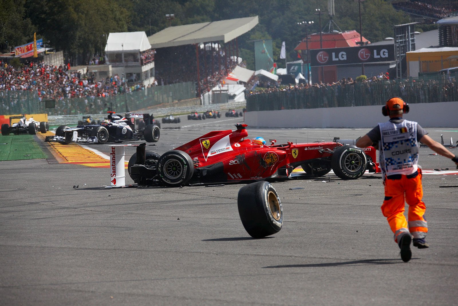 Marshals run to Fernando Alonso in his destroyed Ferrari race car after the start accident