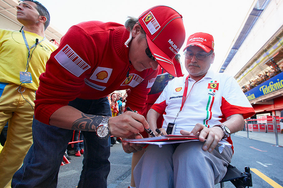 Ferrari driver Kimi Raikkonen signs autographs at thursday pit walkabout