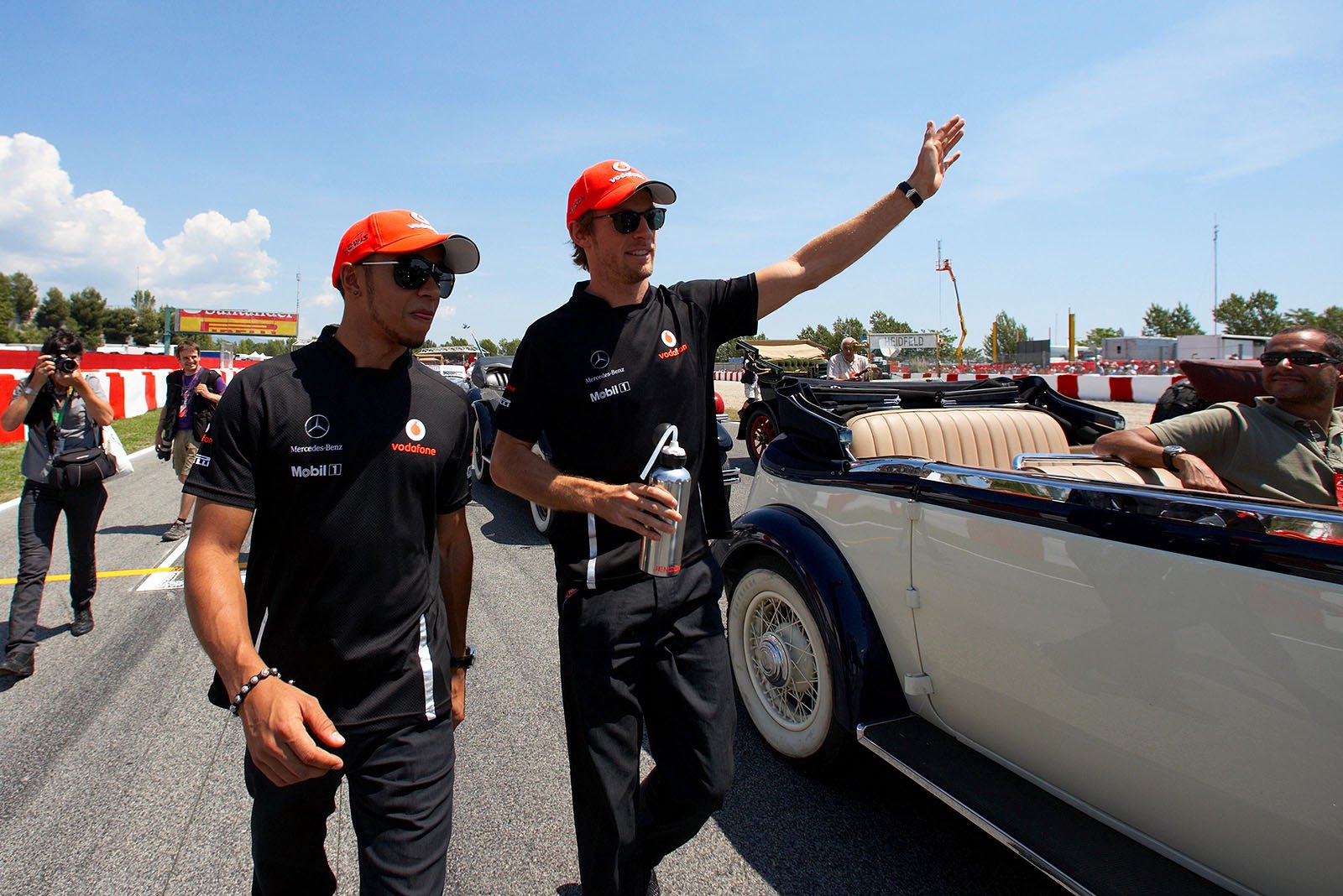 McLaren duo of Lewis Hamilton and Jenson Button sport a rather dark team clothing on a sunny day.