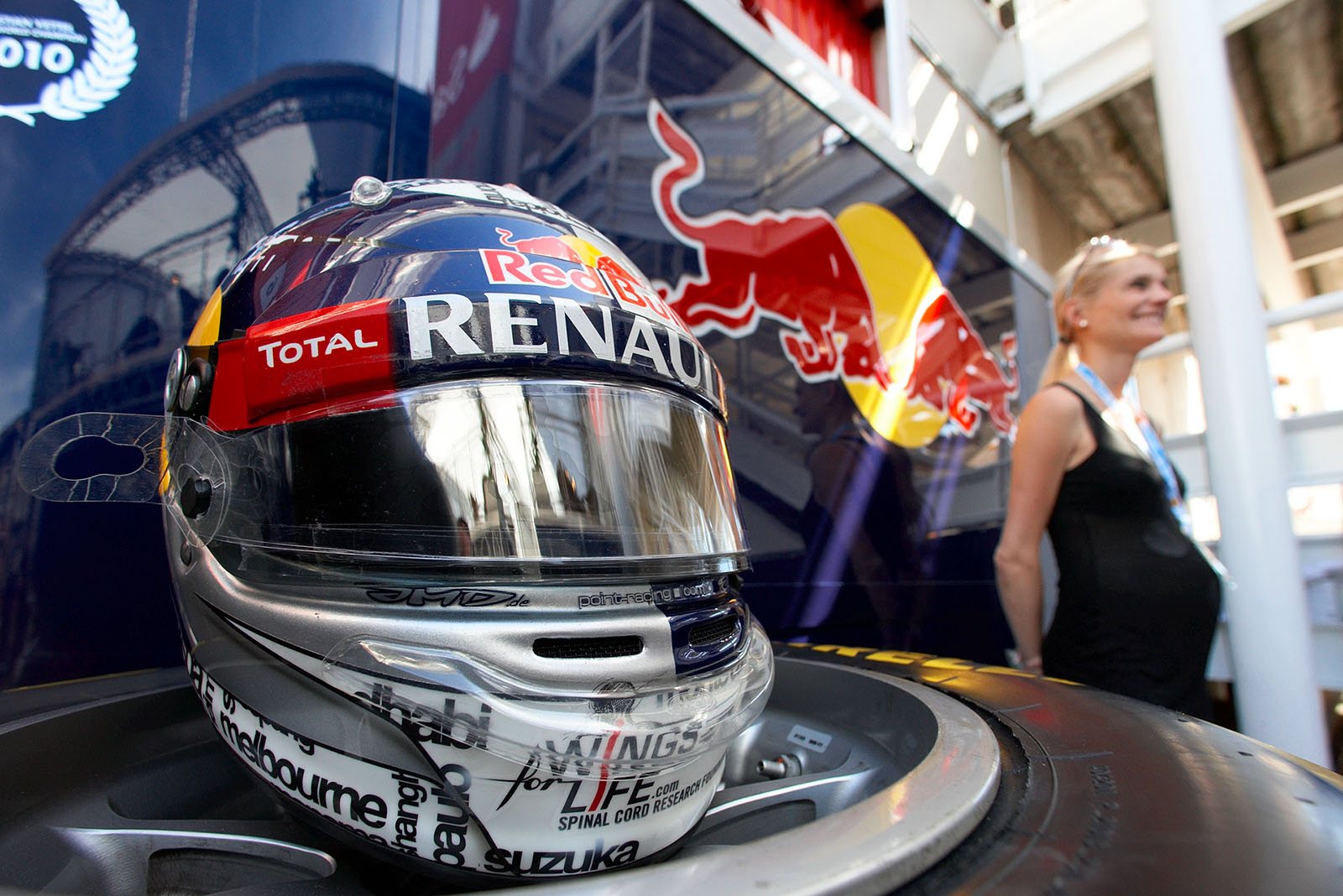 A blonde woman takes a souvenir photo besides Sebastian Vettel's helmet for the Spanish Grand Prix