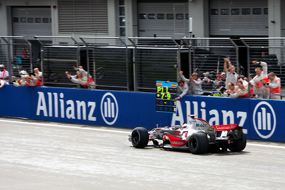 Winner Alonso passes his cheering McLaren team
