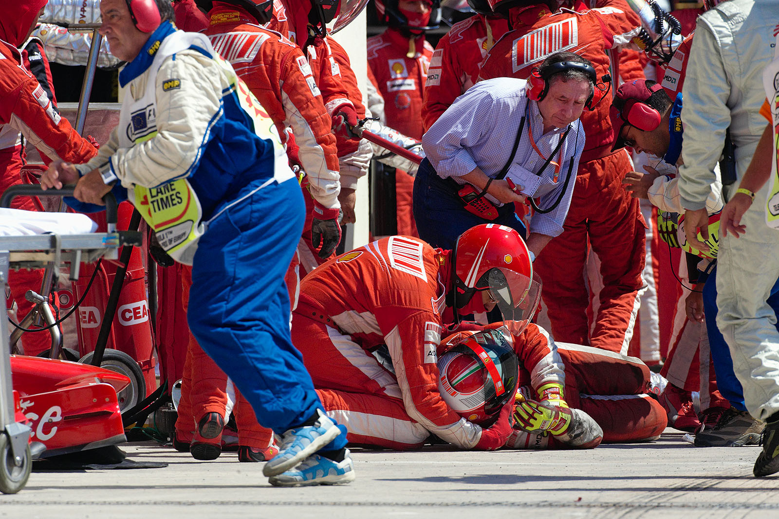 Jean Todt and a Ferrari mechanic look after a tumbled colleague after Kimi's pit stop