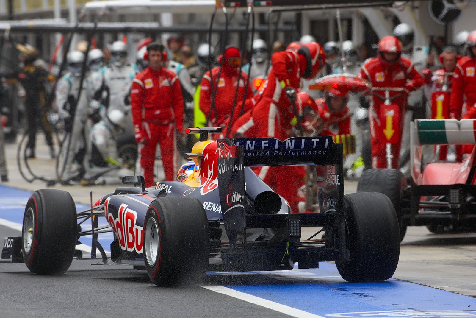 Sebastian Vettel ejects from Red Bull Racing pits and jumps in front of Alonso's pitting Ferrari