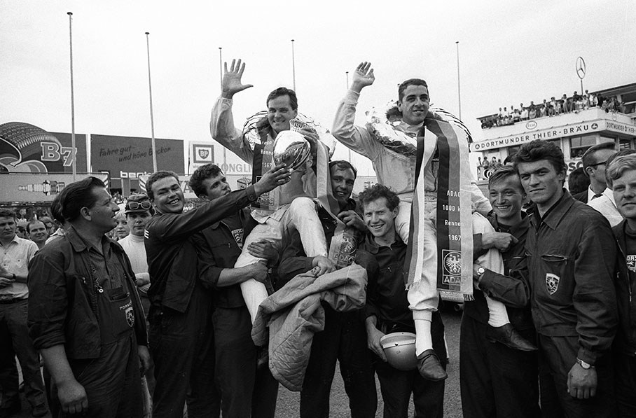 Victorious Porsche drivers Udo Schütz (D) and Joe Buzzetta (USA) are picked from podium by their cheering mechanics
