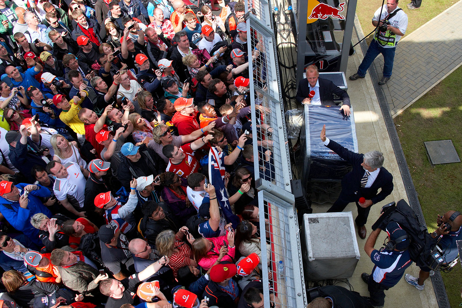 BBC TV presenters and former race drivers Damon Hill and Johnny Herbert are separated from the cheering crowds by the pit wall fence only