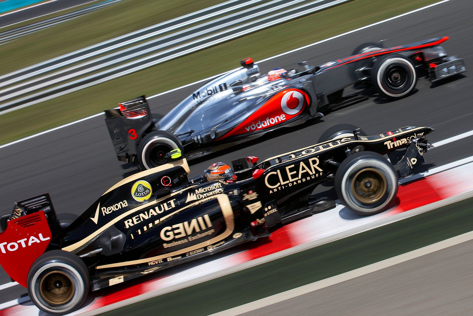 Jenson Button overtakes Romain Grosjean of Lotus F1 team who carries a broken front wing to pits