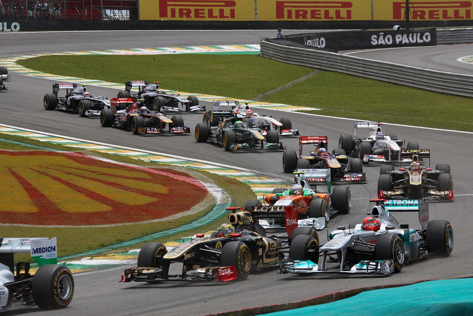 The start field squeezes through turn one, Senna and Schumacher already side-by-side promising a battle for later