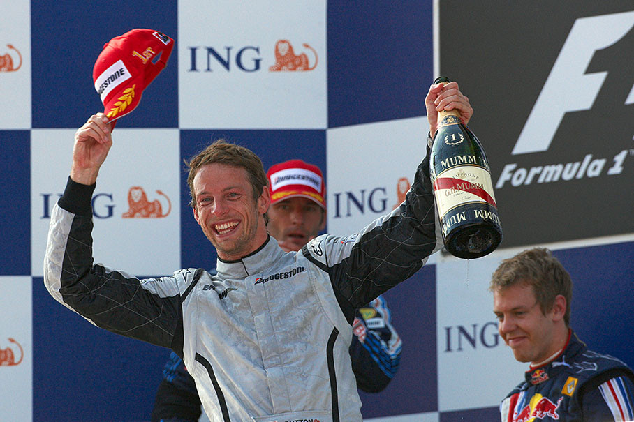 A success-drunk and fresh Jenson Button greets from the podium, celebrating his victory