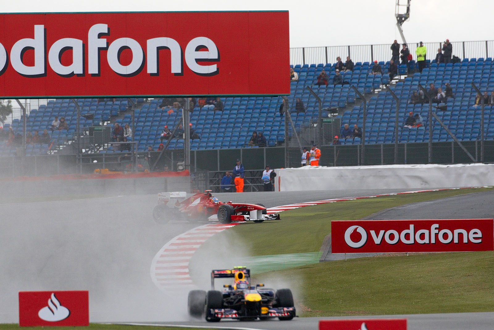 Ferrari's Fernando Alonso transverses over the curbs behind Webber's spray