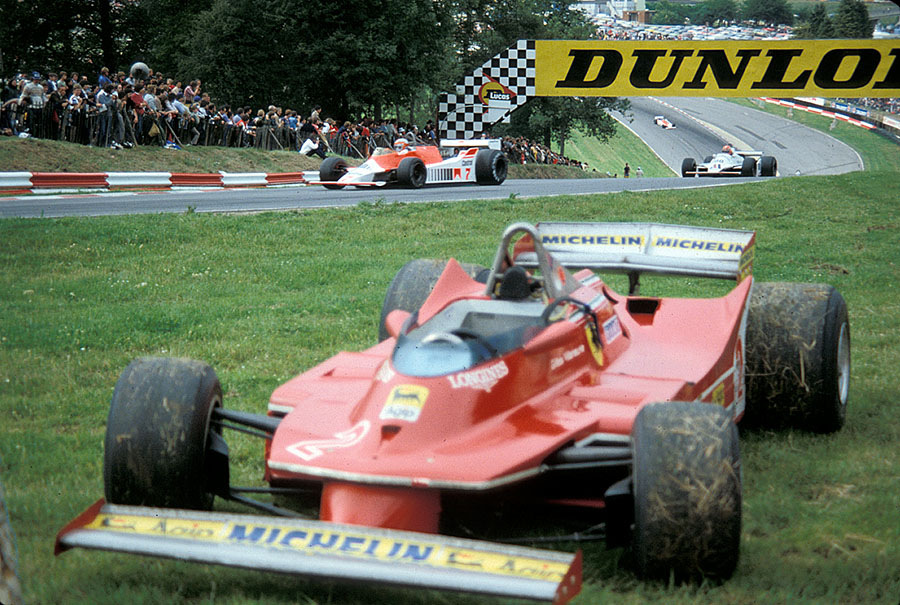Gilles Villeneuve's retired Ferrari is passed by John Watson in a McLaren-Cosworth