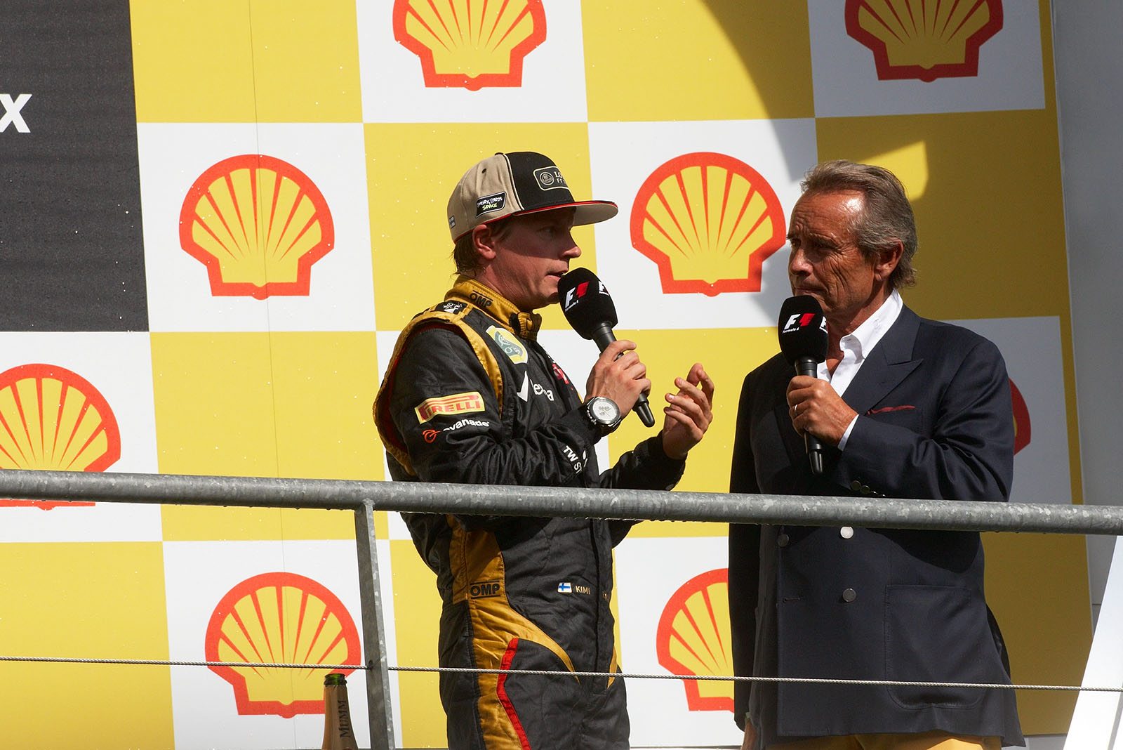 Belgian racing legend Jacky Ickx interviews third placed Kimi Raikkonen on the podium after the ceremony