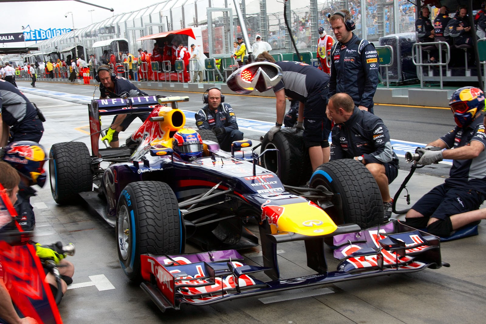 Mark Webber practises stops with the Red Bull Racing pit crew
