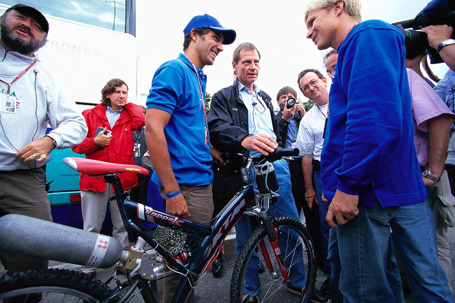 Pedro Diniz and Mika Salo of the Sauber team receiving a new technically equipped bicycle as present