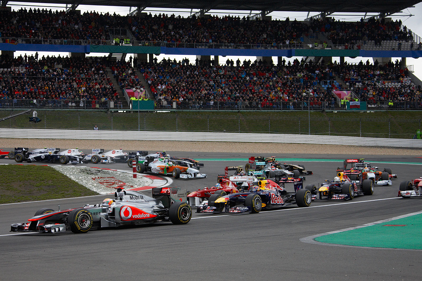 The field goes around turn one, Hamilton leads Webber and Alonso