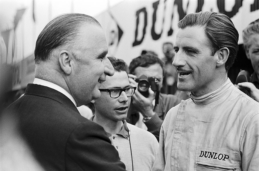 On the grid before the French GP 1965 in Clermont-Ferrand, the Prime Minister of France, Georges Jean Raymond Pompidou, chats with BRM's racing driver Graham Hill and journalist Gerard "Jabby" Crombac