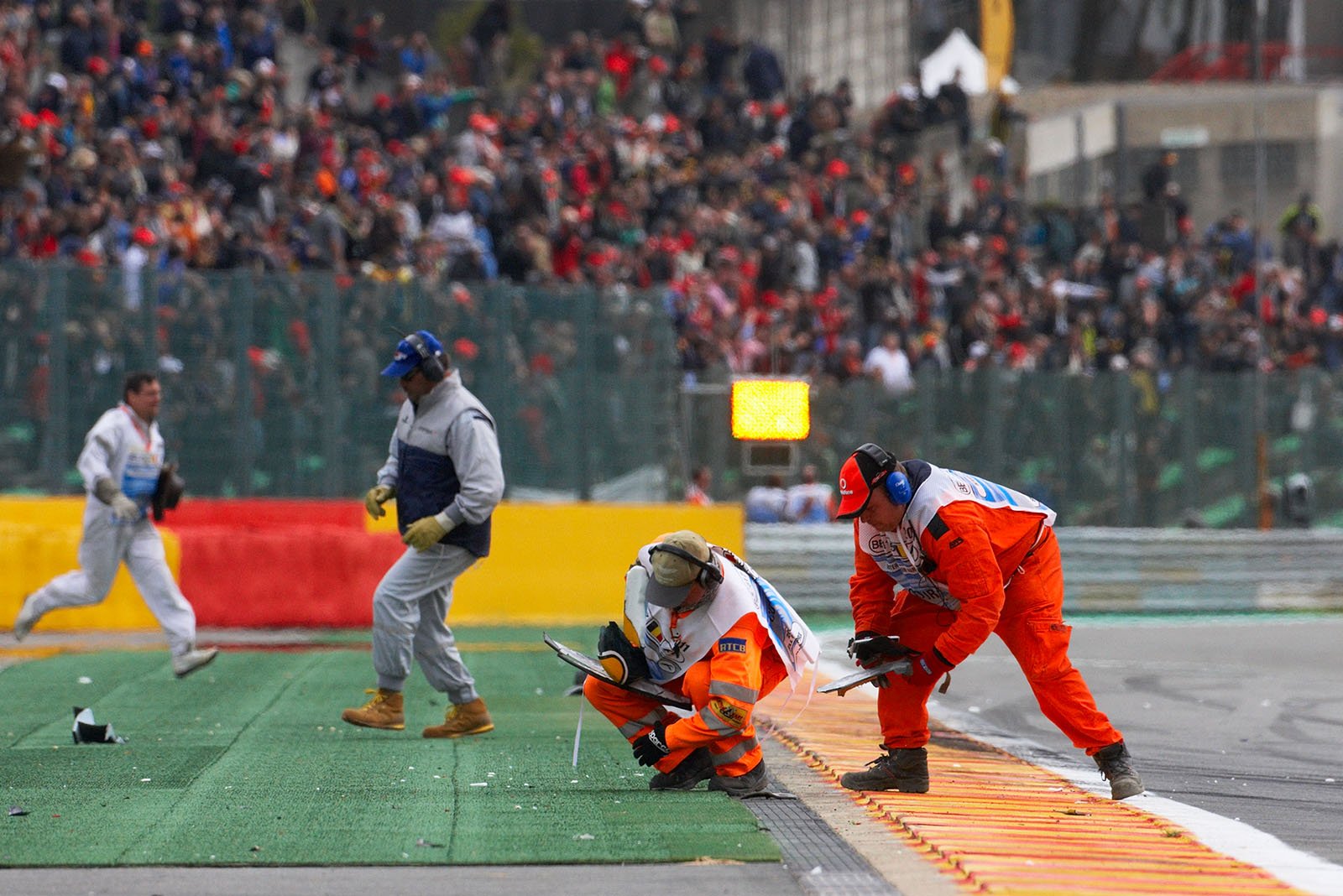 Marshals collect the debris and wing parts after the start collision