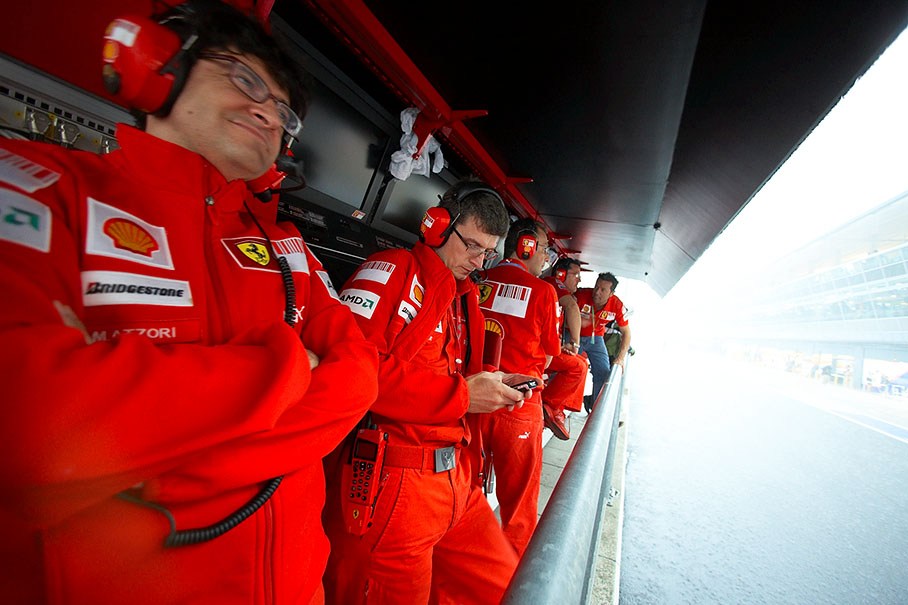 Ferrari pit wall commanders await the end of Friday morning's heavy rain