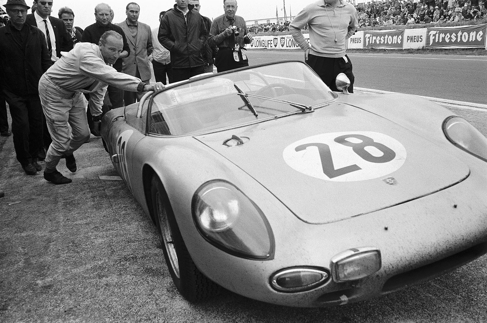 Followed by compassionate journalists, Edgar Barth (DDR) pushes his Porsche 718 WRS #047 without the right rear wheel through the pitlane towards his pit crew,  no help allowed by racing rules! He will finish the 24h race in 8th position, 39 laps behind the winner.