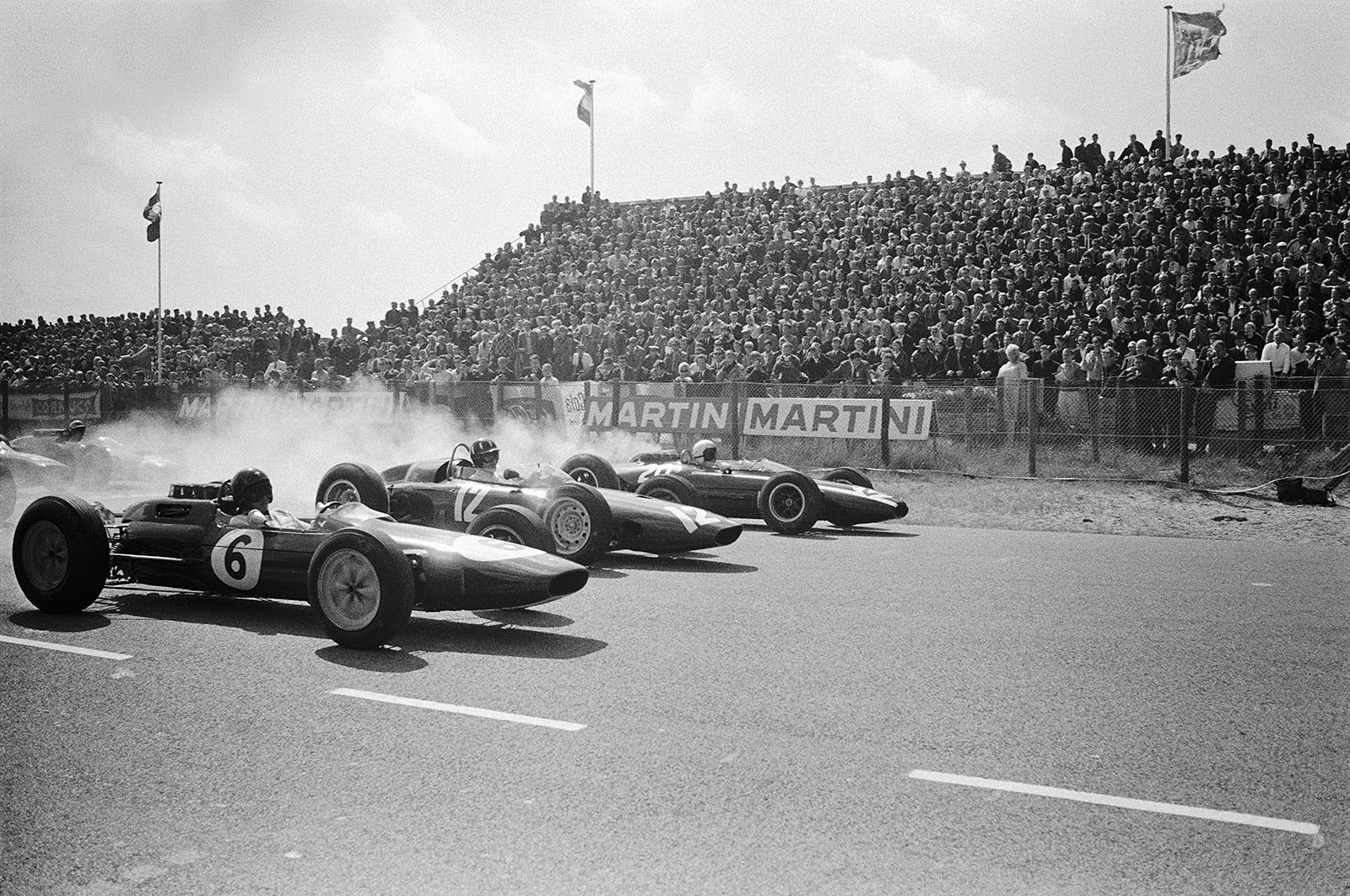 Start of the Dutch Grand Prix 1963: Smoking wheels in first row from later race winner Jim Clark (Lotus Climax 25, #6), Graham Hill (BRM P57, #12) and Bruce McLaren (Cooper-Climax T66, #20)