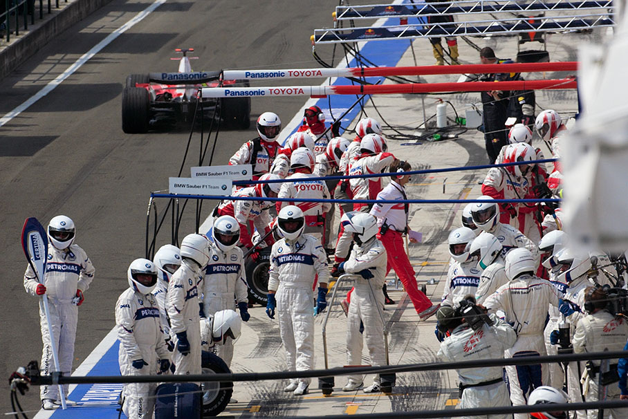 Whilst Ralf Schumacher pits out, BMW Sauber mechanics await Robert Kubica for a pit stop