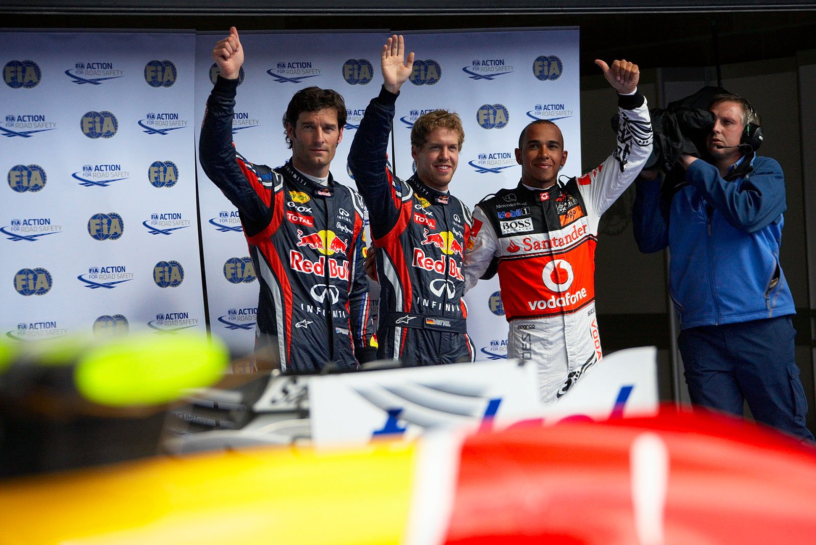 The fastest three qualifiers wave at the world's media: on the right hand third qualified McLaren's Lewis Hamilton, Red Bull driver Sebastian Vettel as polesetter in the middle and his team mate Mark Webber as second on the grid on the left