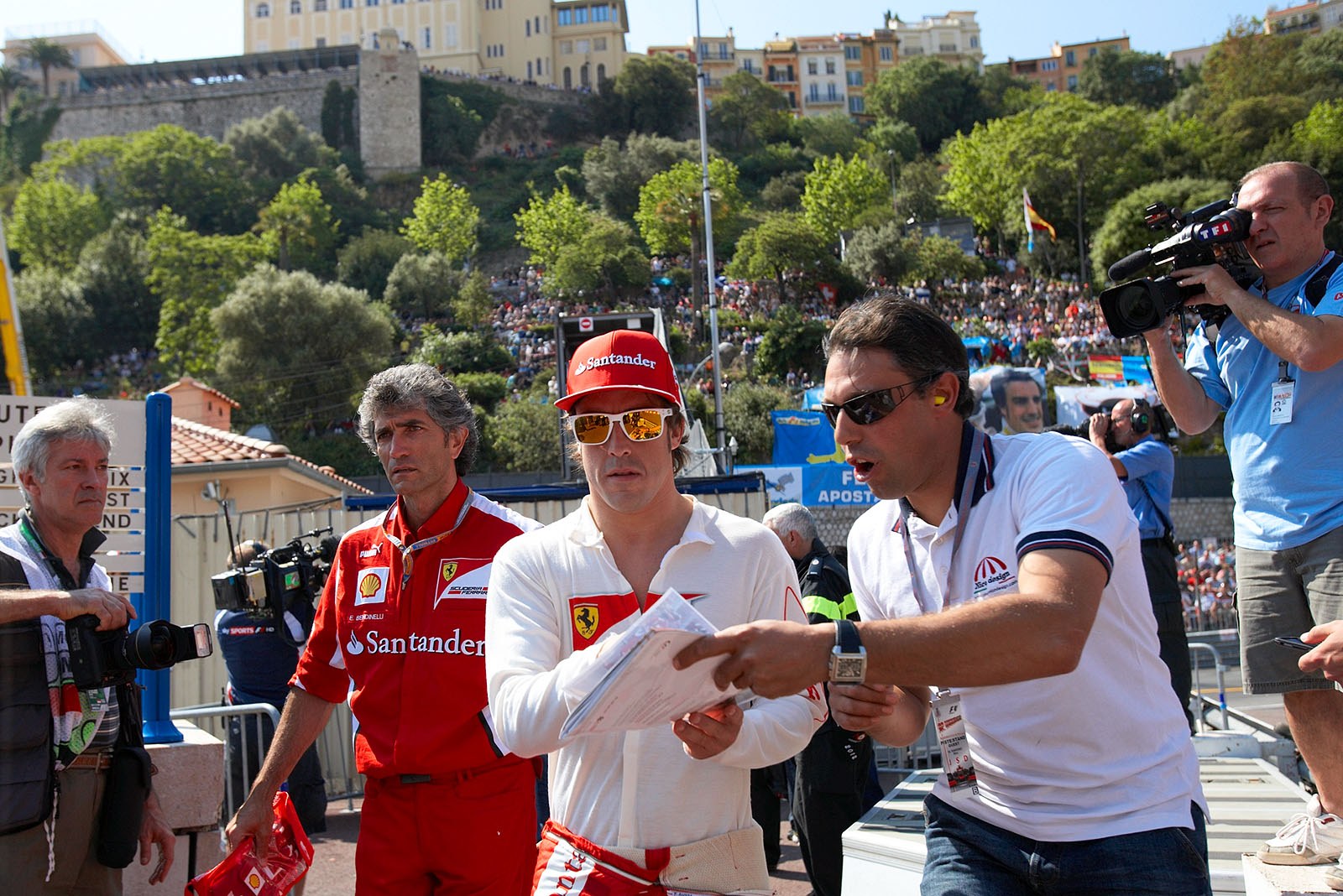 Fernano Alonso quickly gives an autograph on his way to the pits