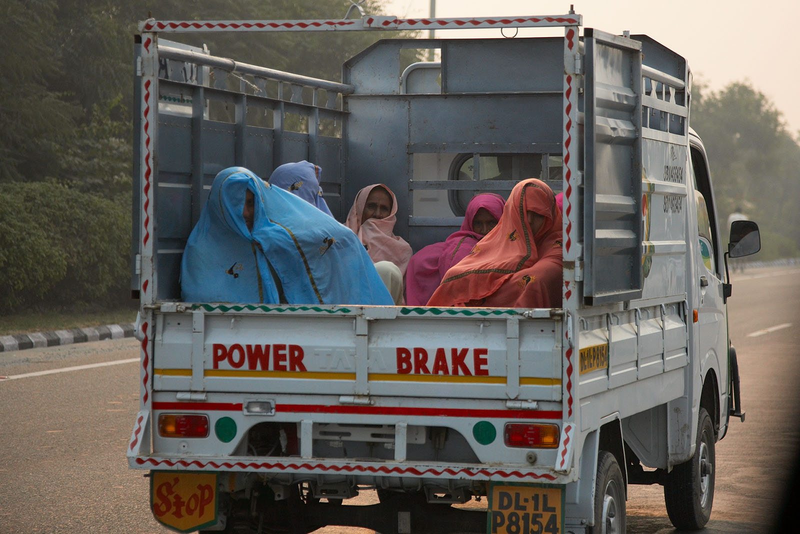 Covered women are carried on the load area of a lorry