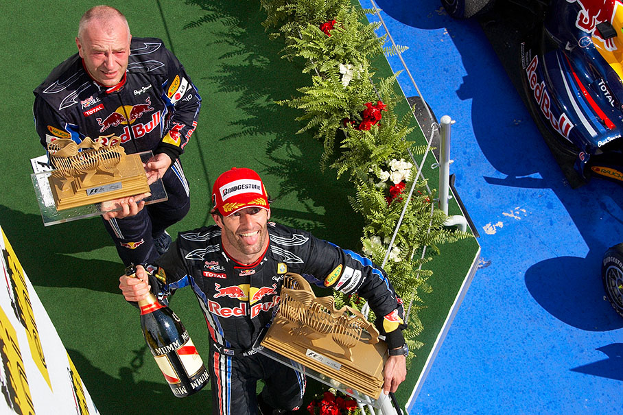 Red Bull Racing mechanic Darren Nicholls and race winner Mark Webber carry their achievements from the podium in Hungary
