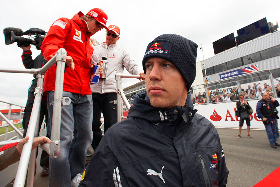 Polesitter Sebastian Vettel climbs down from the drivers parade truck in front of the two Finns Raikkonen and Kovalainen