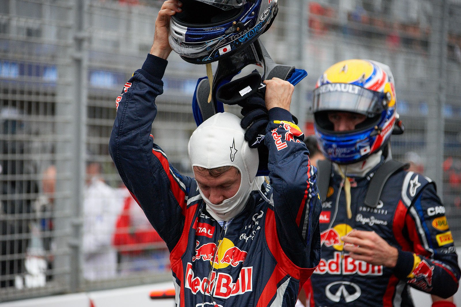 Red Bull team mates Sebastian Vettel (who takes his helmet off) and Mark Webber return together from qualifying - Vettel as polesetter, Webber as third on grid