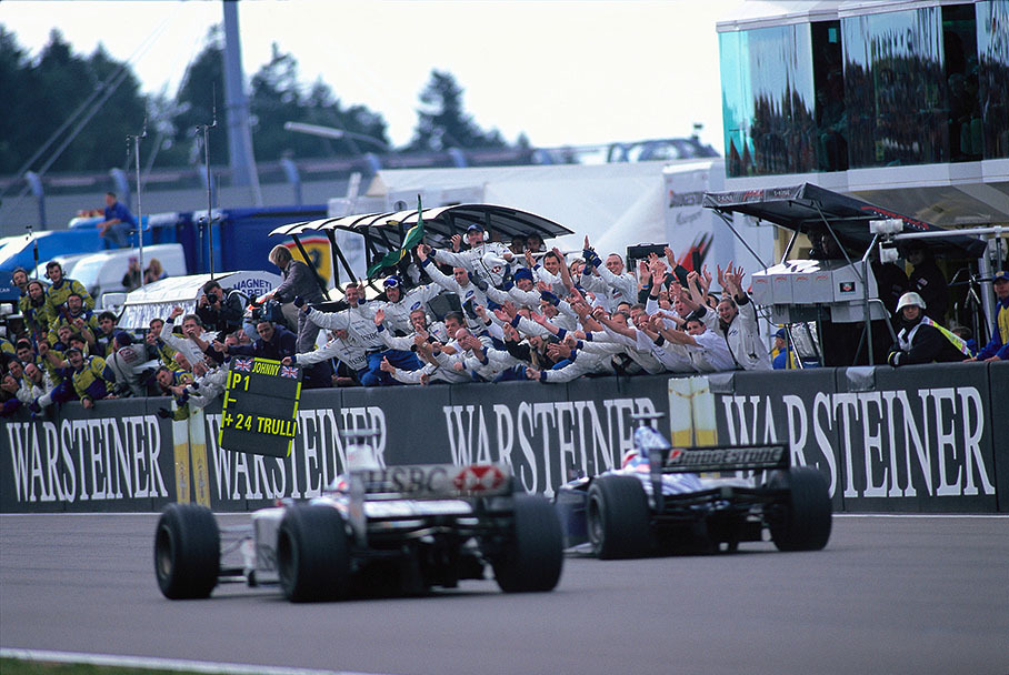 1st victory for Stewart Racing: Johnny Herbert is being welcomed by his cheering team behind the finish line.