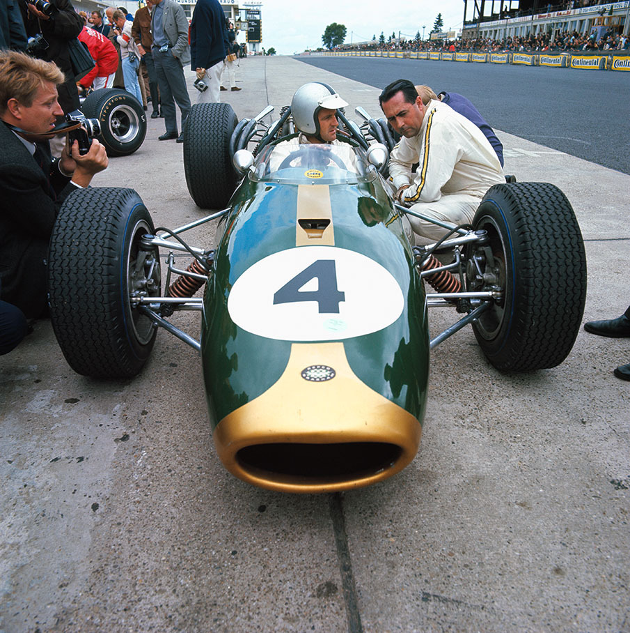 The two drivers of the Brabham team: Denny Hulme sitting in his car, talking to teamowner Jack Brabham.