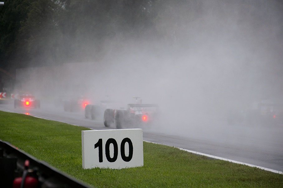 A cloud of spray with blinking red lights roars through first chicane