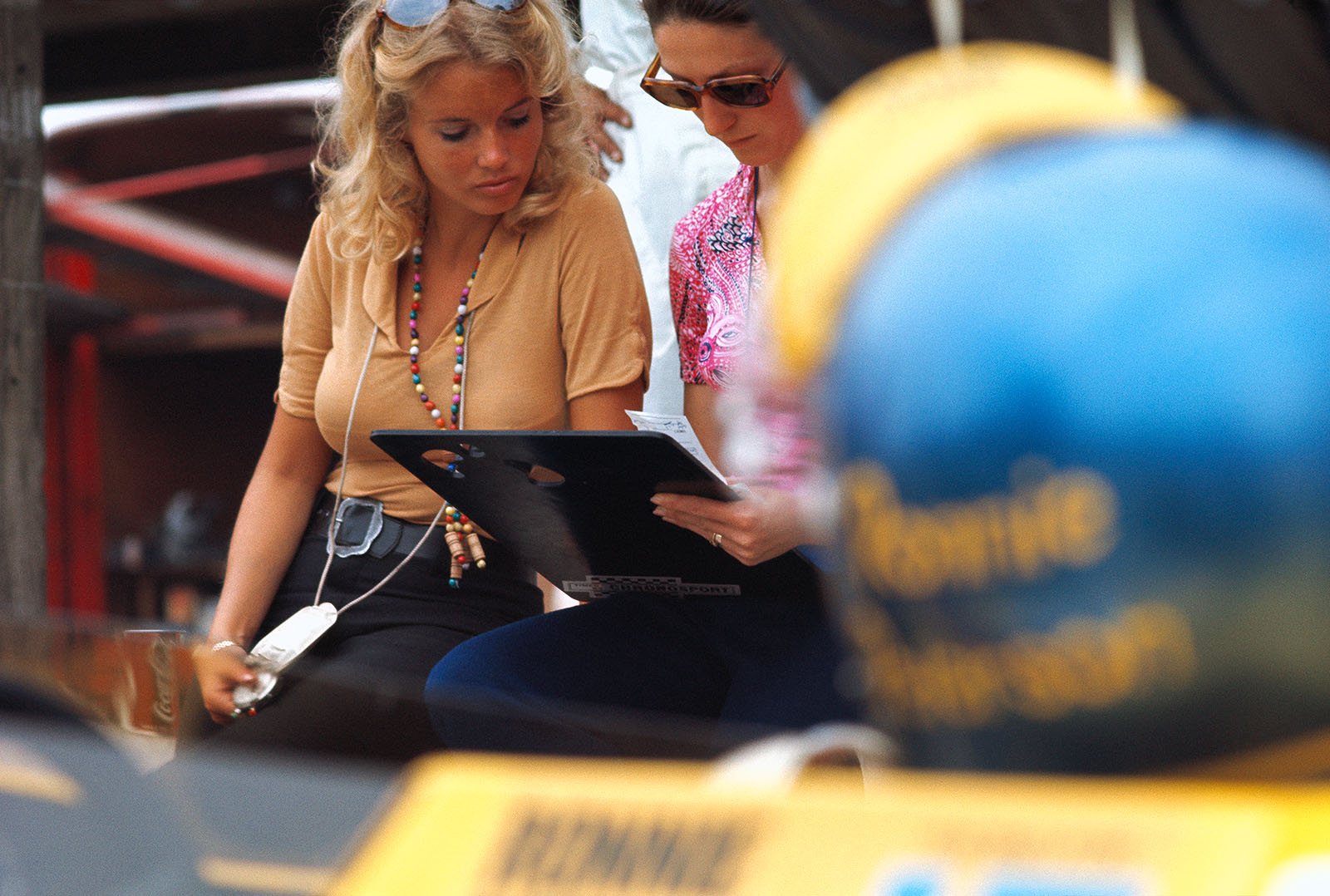 Barbro Peterson keeps her husband Ronnie's times (you can see Ronnie's helmet in the foreground) together with Siffert's wife Simone in March pits during the German GP weekend 1970