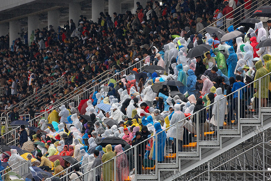 Korean race fans withstand the heavy rain on an open stand